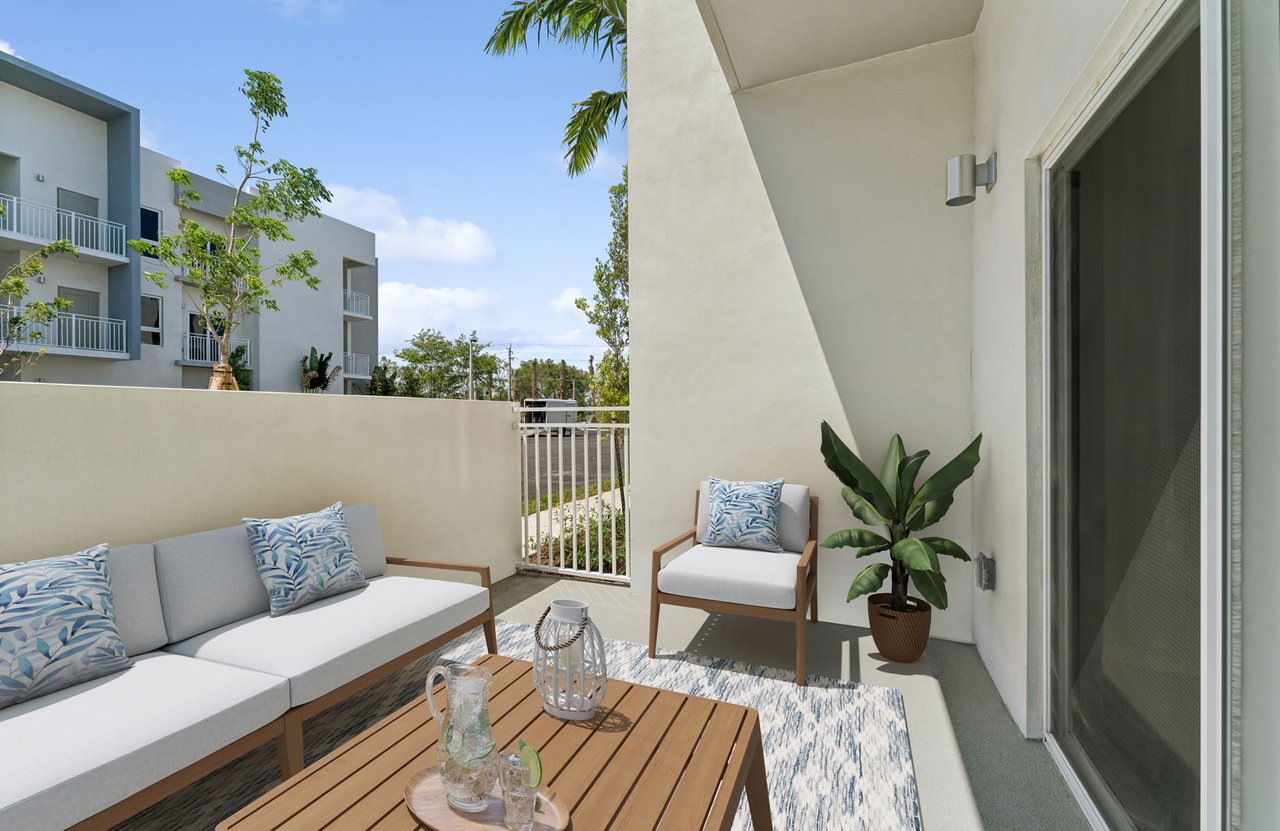 Furnished balcony with white-cushioned seating, a wooden table, and views of neighboring modern buildings.