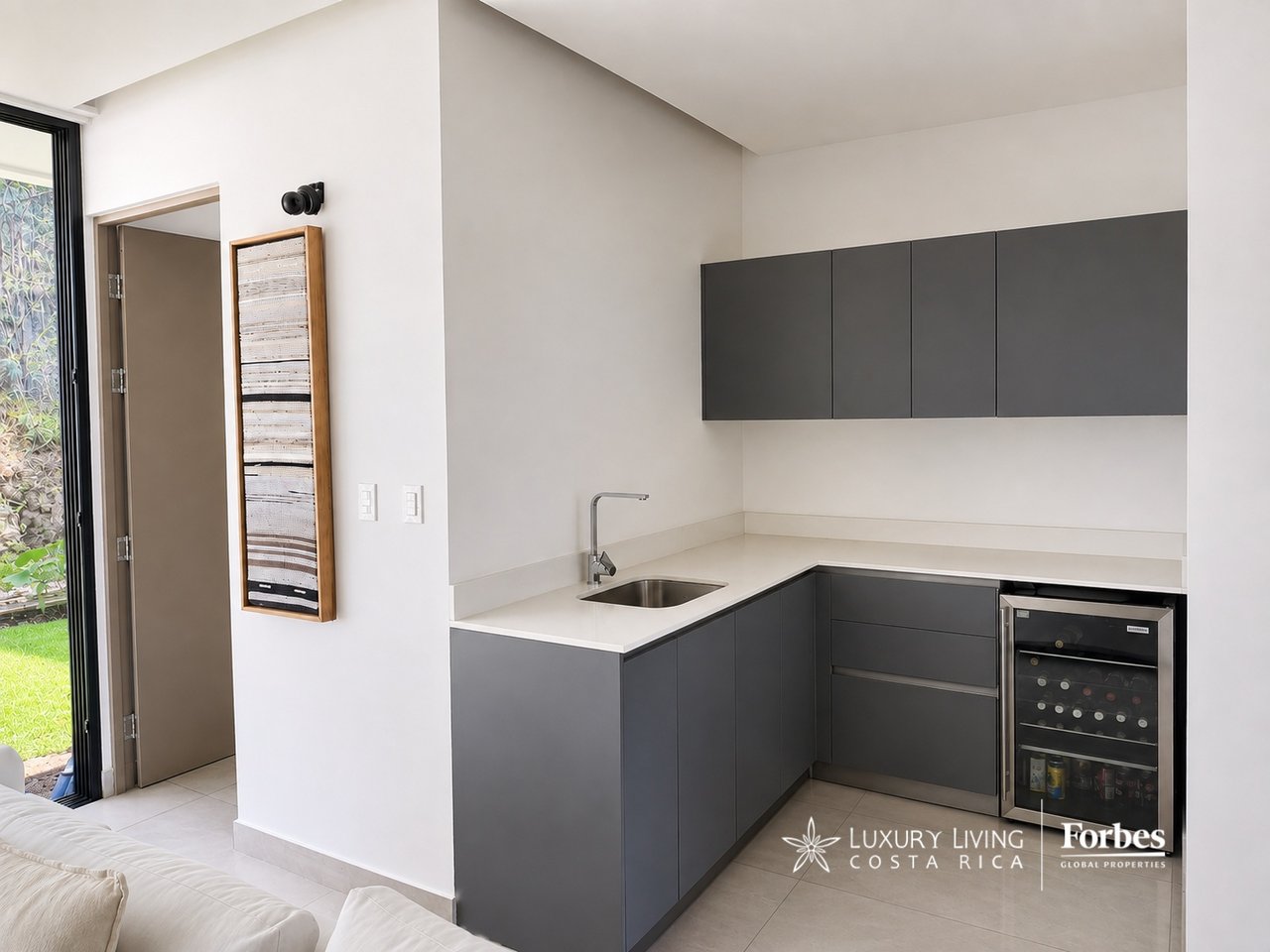 Modern kitchen with charcoal cabinets, white counters, and a glass-front wine refrigerator.