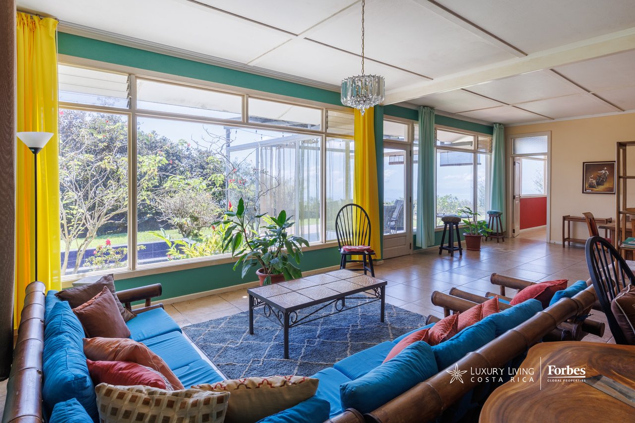 Living room with blue sofas and floor-to-ceiling windows framed by yellow curtains.