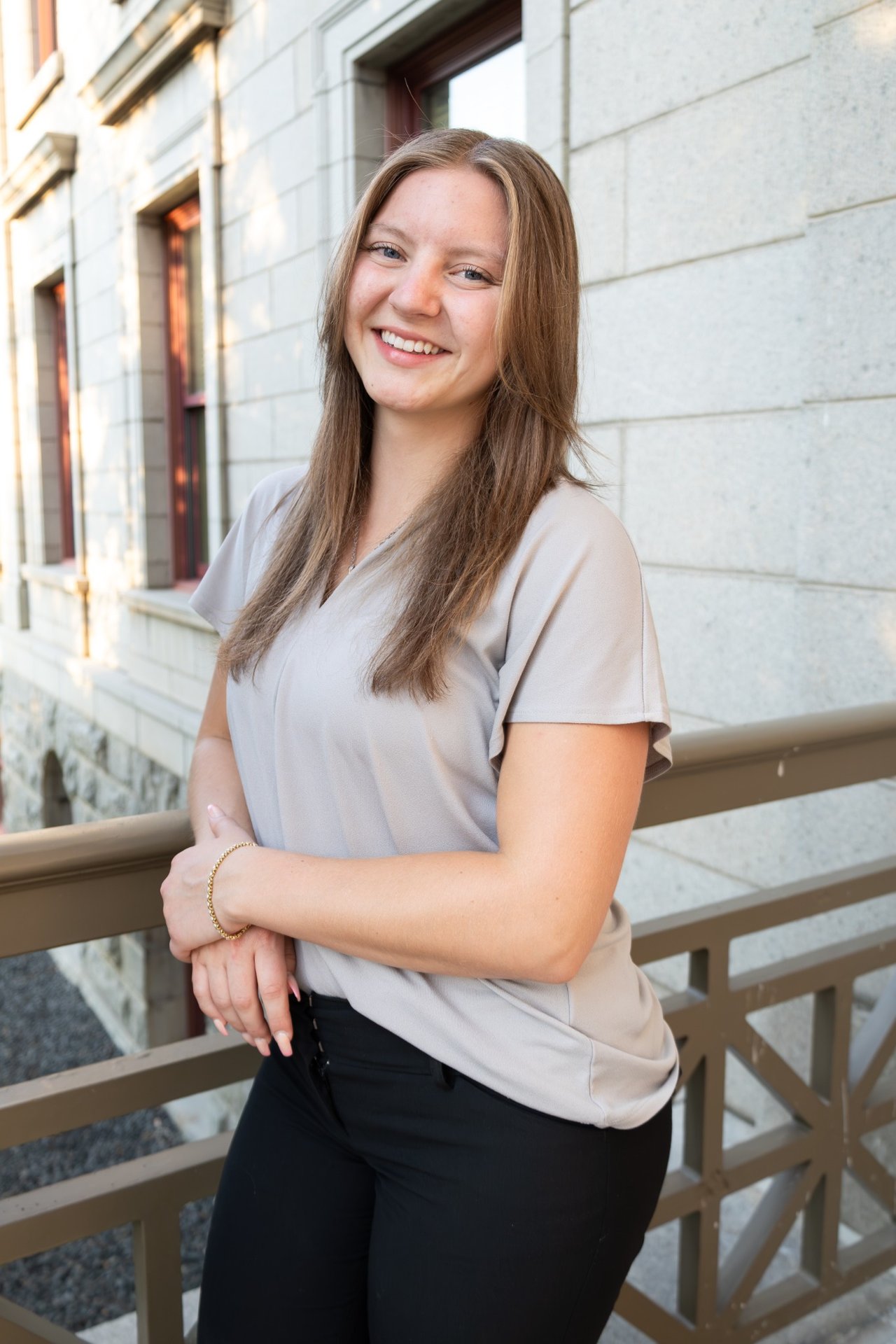 Adelyn Nowlan smiles beside a stone building, leaning on a railing.