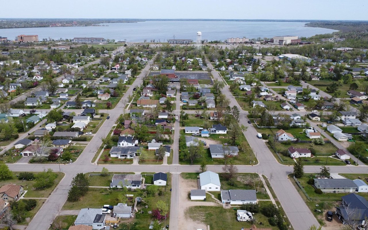 Aerial neighborhood of detached homes beside a lake, with a water tower near the shoreline.