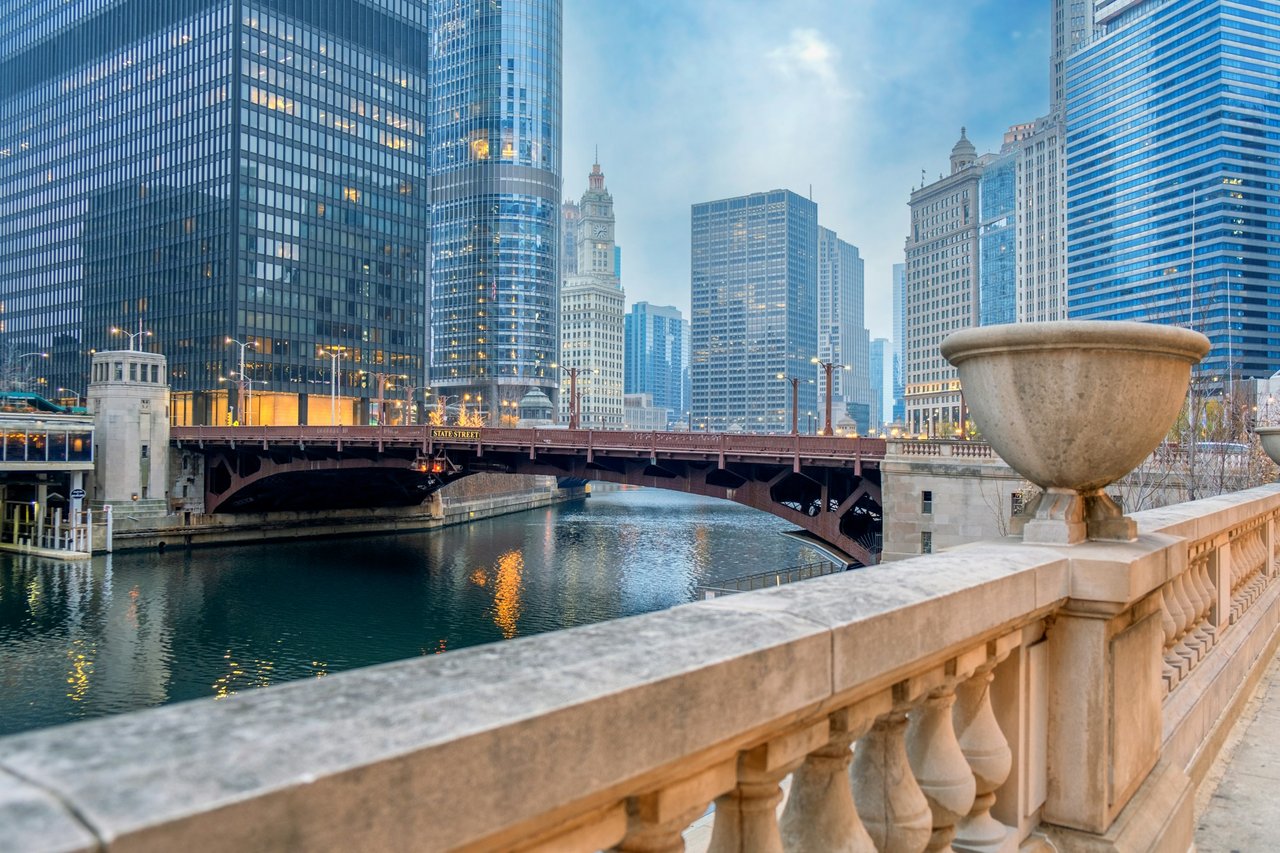 Chicago River and downtown skyline viewed past the State Street Bridge and stone balustrade.