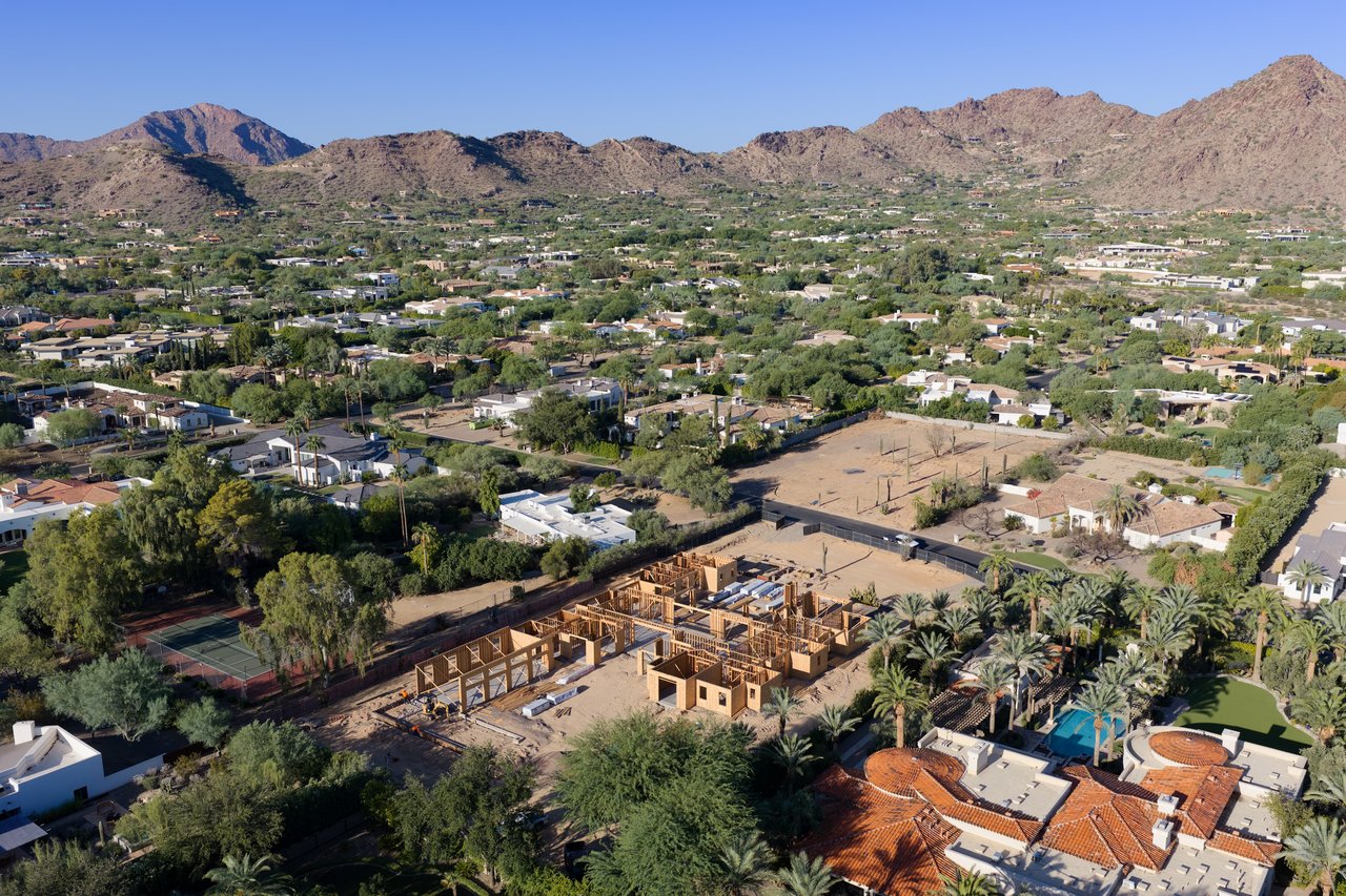 Aerial view of a home development under construction, with mountain ranges beyond the surrounding neighborhood.