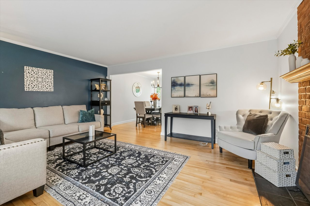 Living room with a navy accent wall, patterned rug, hardwood floors, and adjoining dining area.
