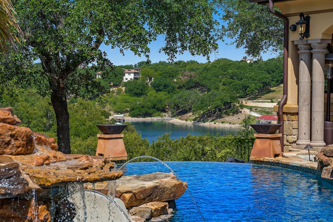 Negative-edge pool with a stone waterfall feature overlooking the Lake Travis cove at 25715 Cliff Circle, Lakecliff on Lake Travis, Spicewood, Texas.