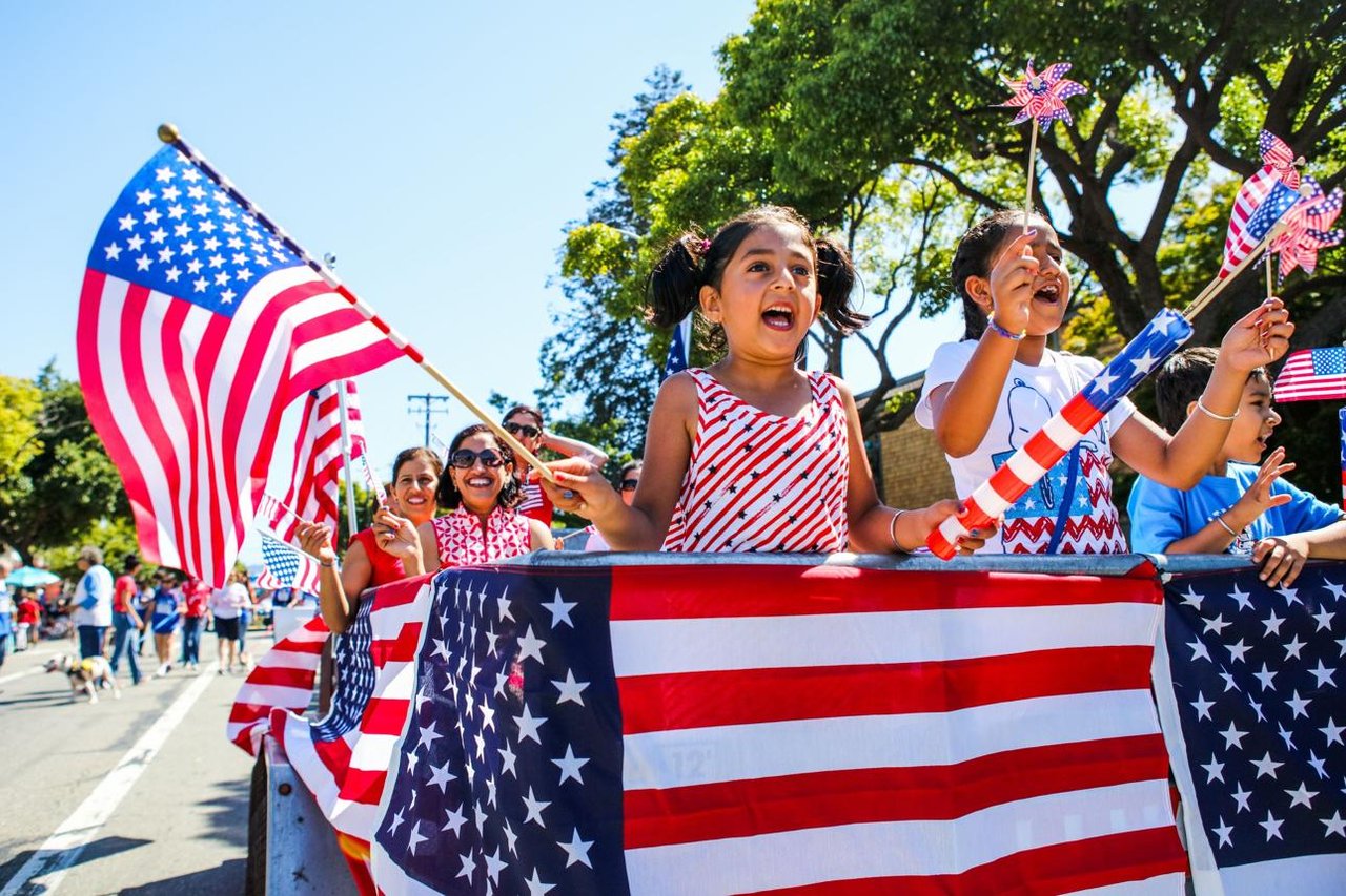 Families enjoying a patriotic Fourth of July festival with flags, music, and activities.