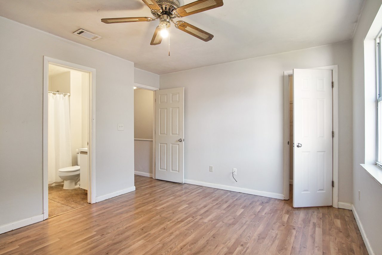 A room featuring a ceiling fan and a toilet, showcasing a simple and functional interior design.