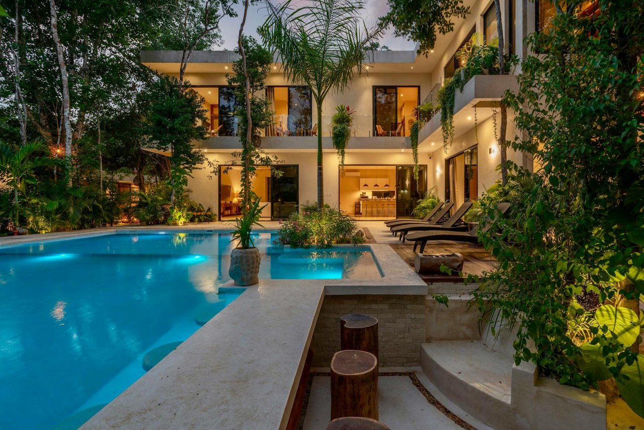 Luxury tropical villa with private swimming pool, lush landscaping, and modern open-concept design at night
