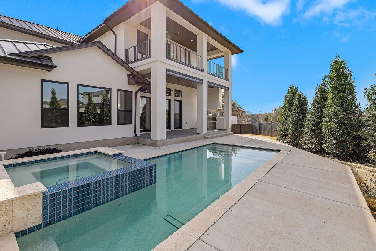 Modern home with covered balconies beside a swimming pool and raised tiled spa.