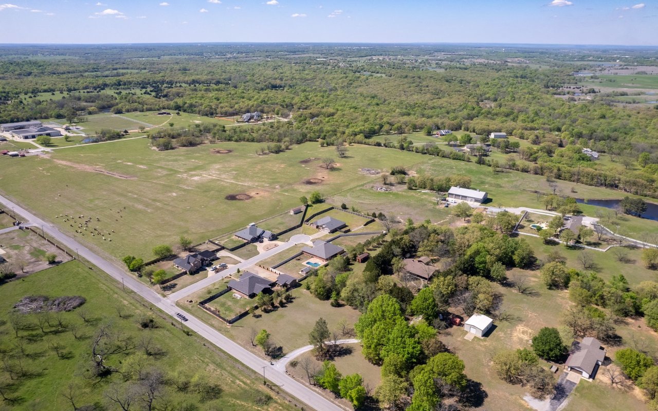 Aerial view of scattered homes and open pastureland surrounded by trees.