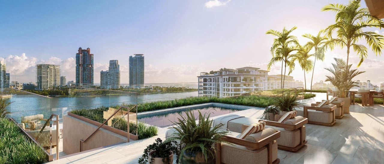 Rooftop terrace with a pool and palm-lined lounge seating overlooking the water and Miami skyline.