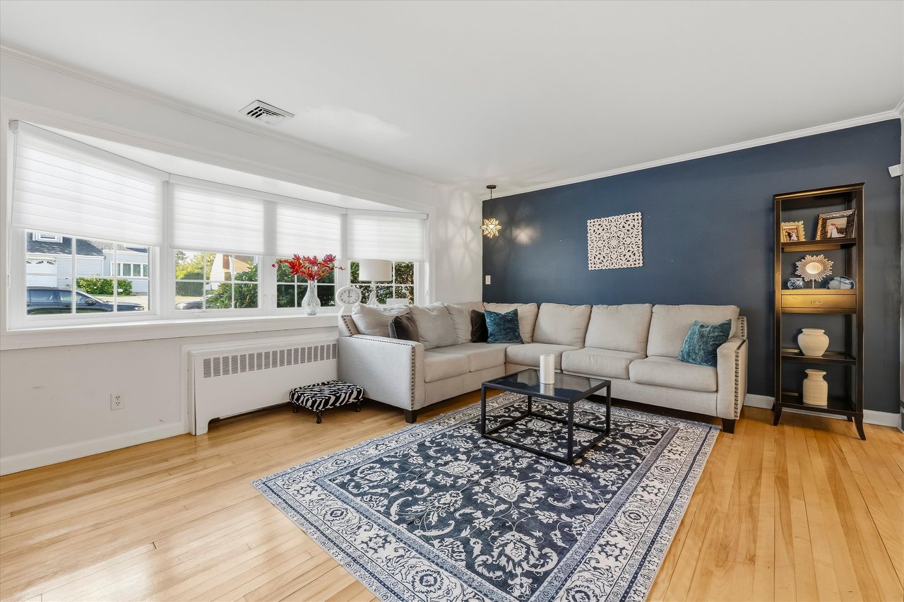 Living room with a beige sectional, blue accent wall, large windows, and patterned rug.