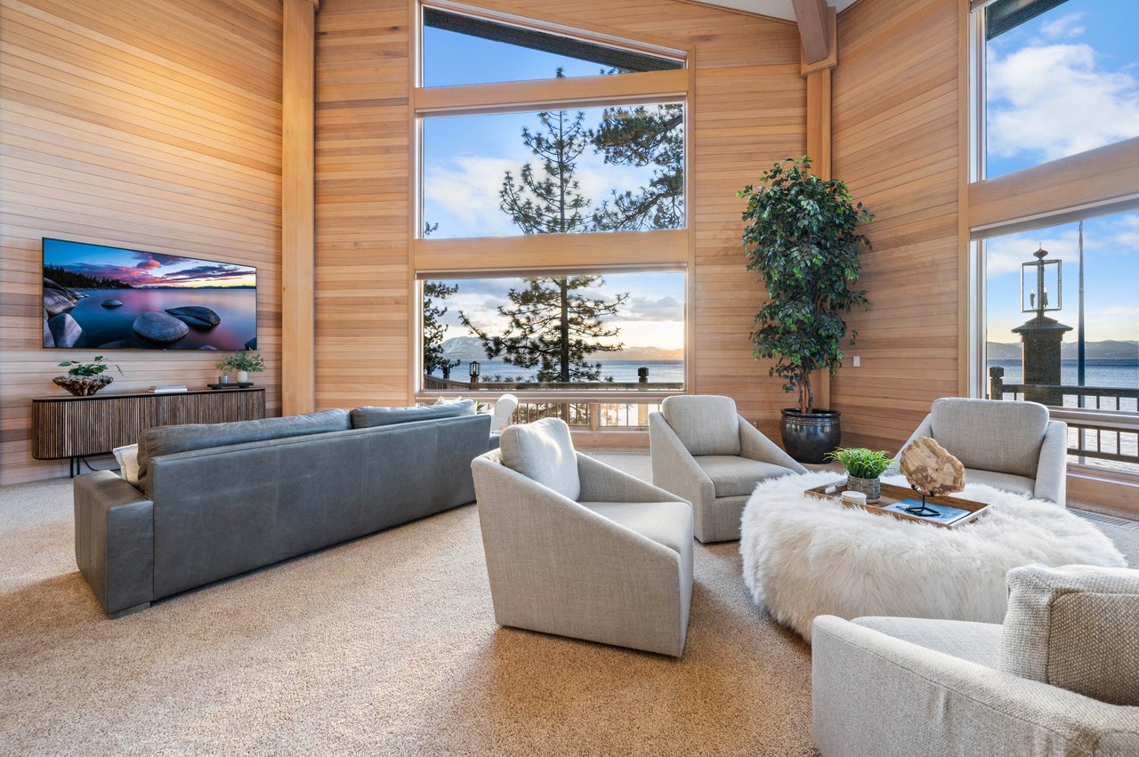 Living room with soaring wood-paneled walls, tall windows, and a lake view.