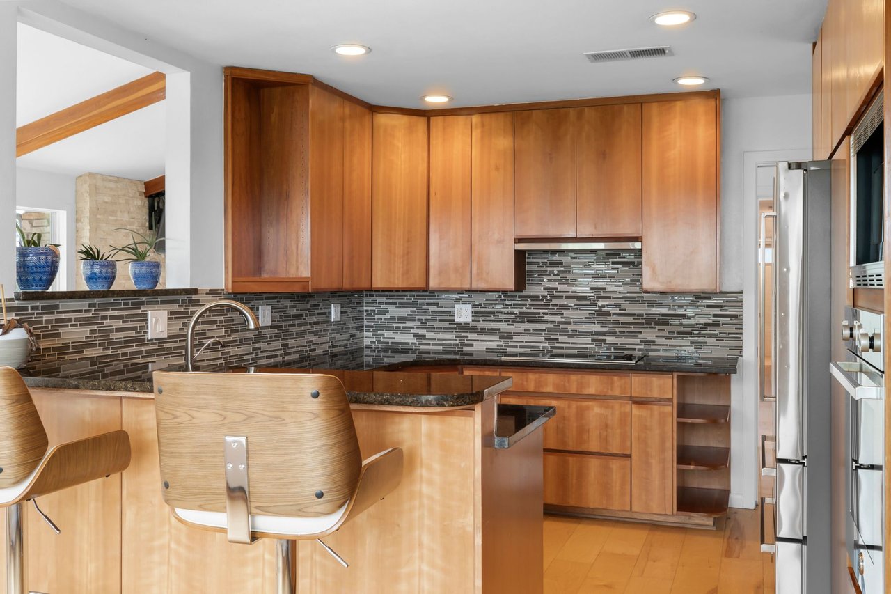 Kitchen prep area with dark granite countertops and mosaic tile backsplash at 3935 Lago Vista Drive, a Mid-Century Modern hilltop home near Lake Travis in Austin, TX (Highland Club Village).