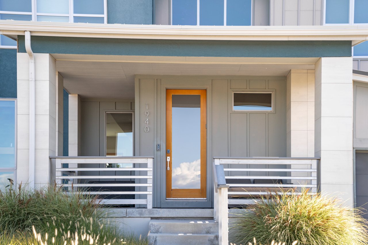 Covered front porch with a glass-paneled wood front door and white horizontal railings