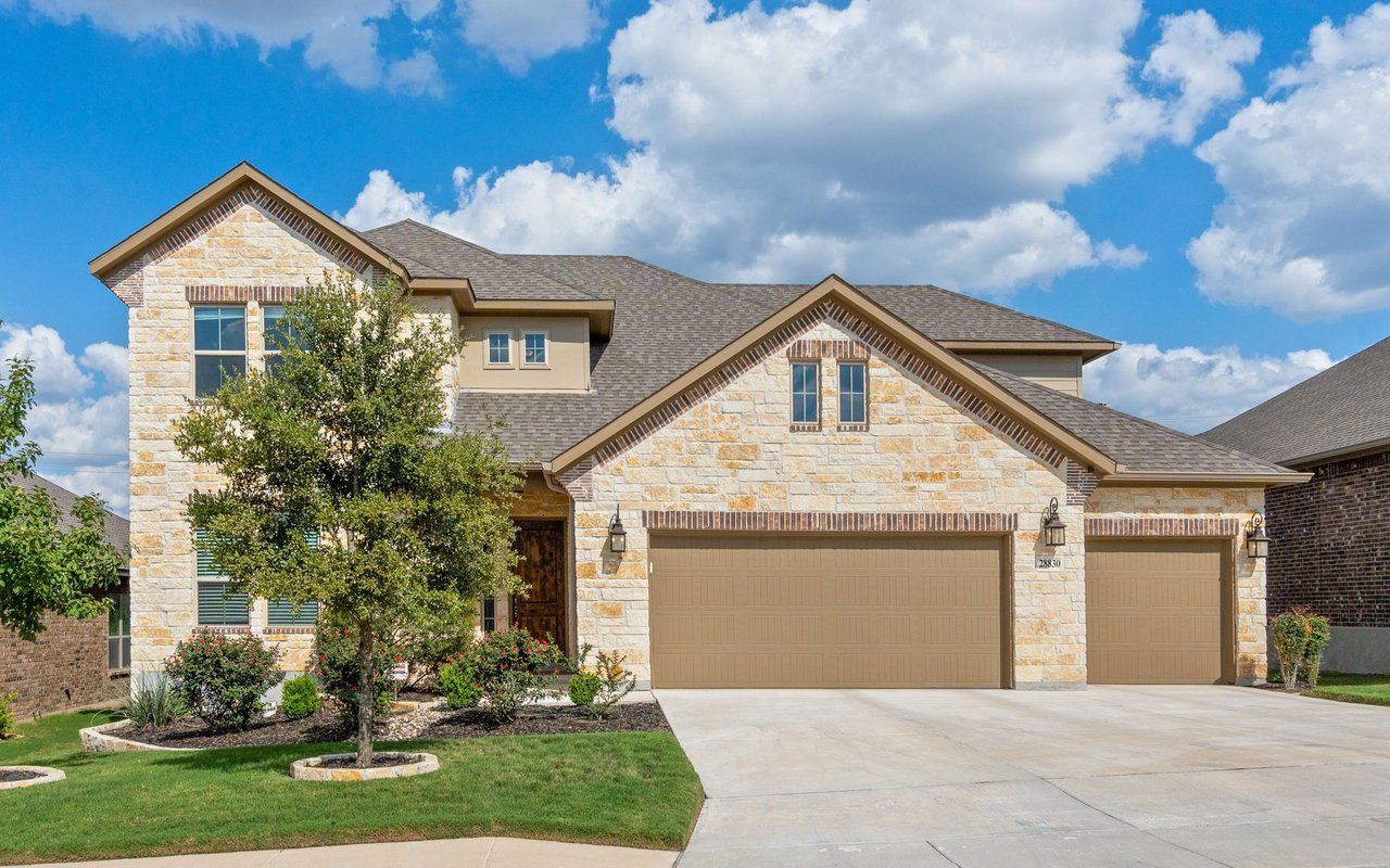 Two-story stone-and-brick house with two garage doors and a landscaped front lawn.