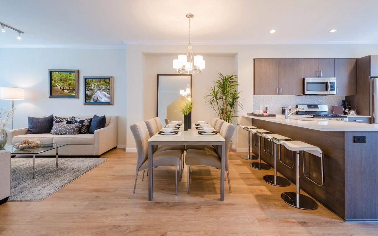 Open-plan living and dining area beside a kitchen island with bar stools.
