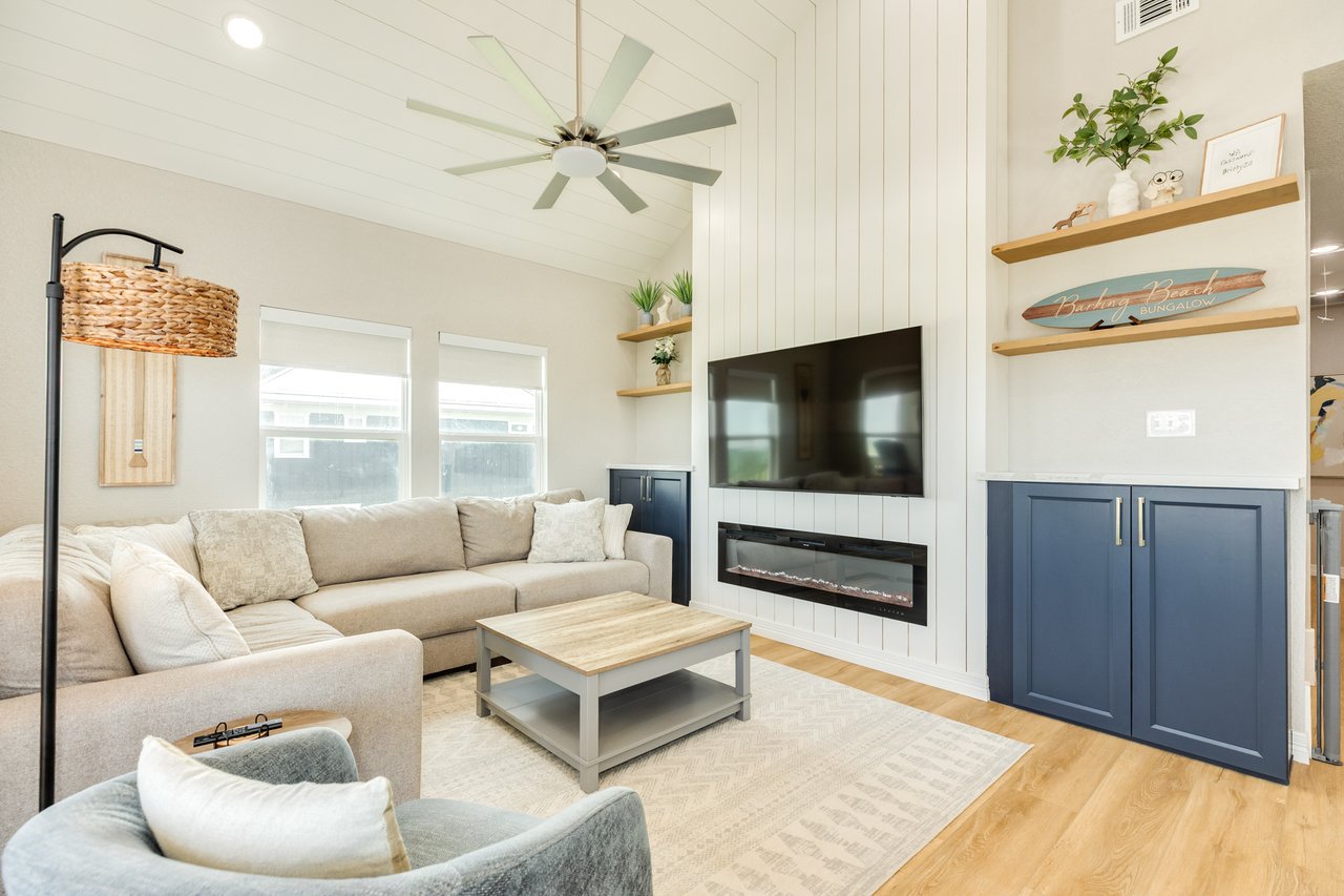 Beach house living room with a cream sectional, paneled TV wall, fireplace, and navy built-in cabinets.