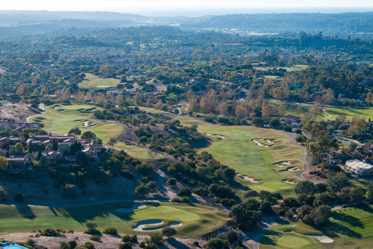 Aerial view of the Santaluz golf course and homes in the rolling hills of San Diego, with the coast in the distance