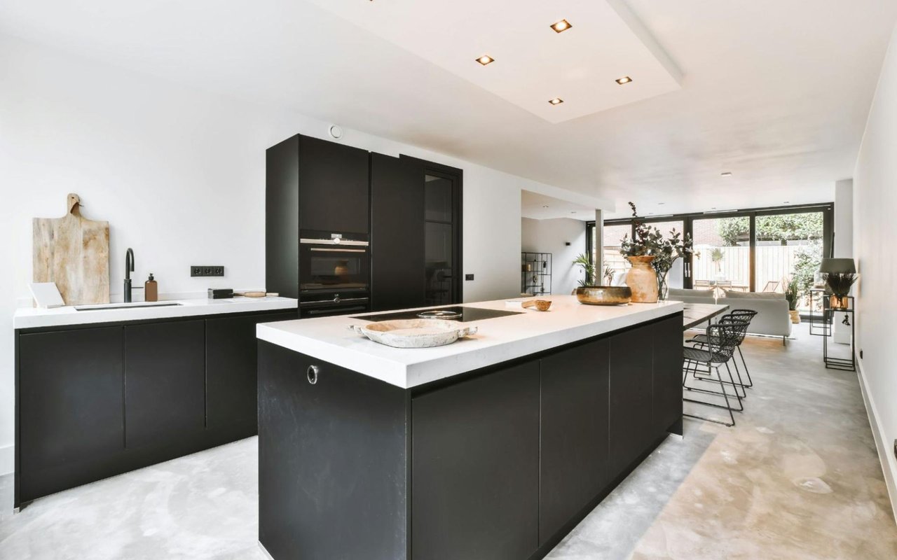 A spacious and modern kitchen featuring matte black cabinetry and white countertops. 