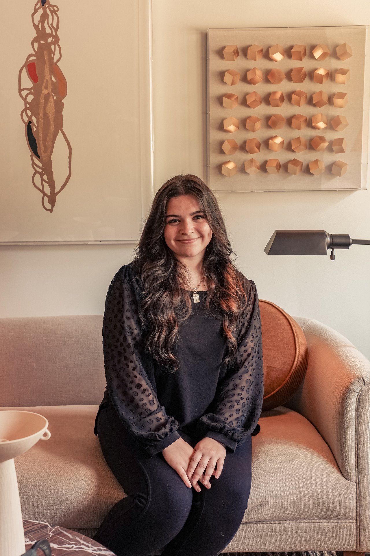 Kylie Norton seated on a beige sofa beneath framed artwork.
