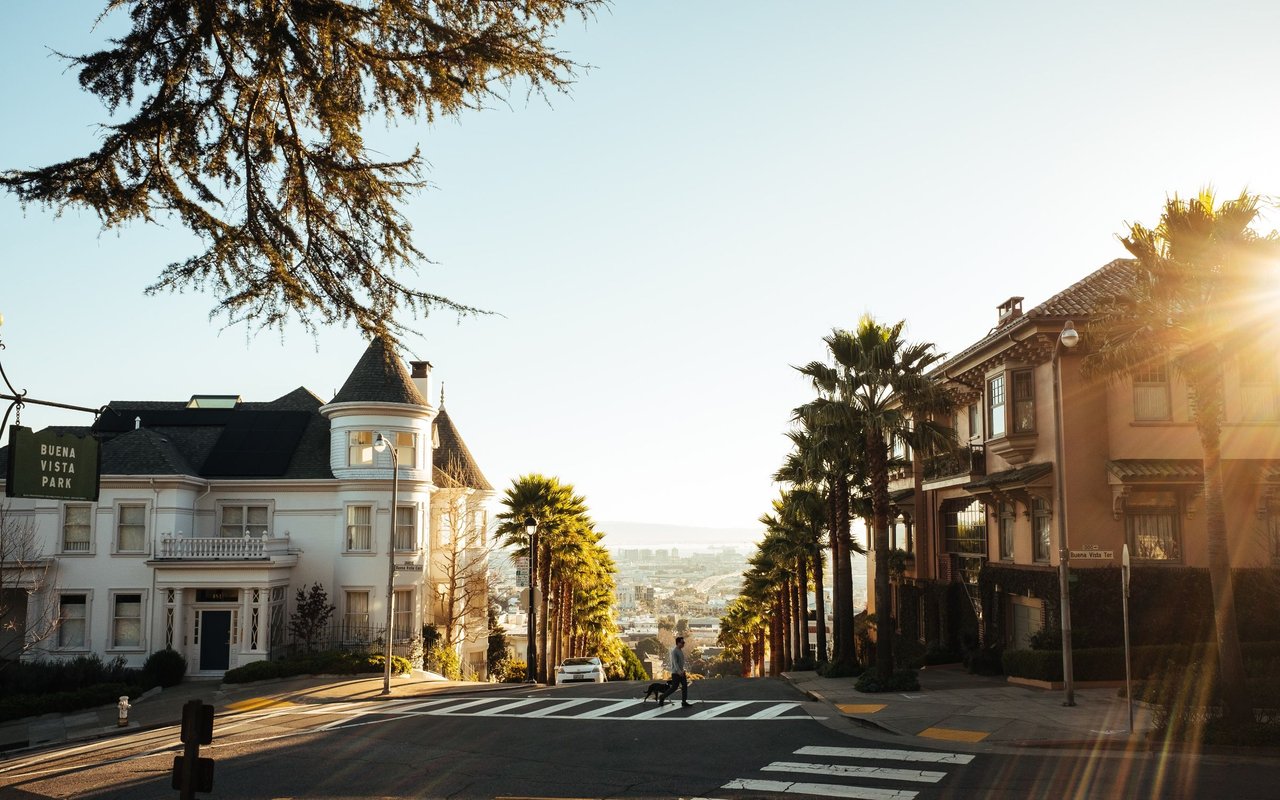 Residential street descending past ornate homes and palm trees in golden-hour light.
