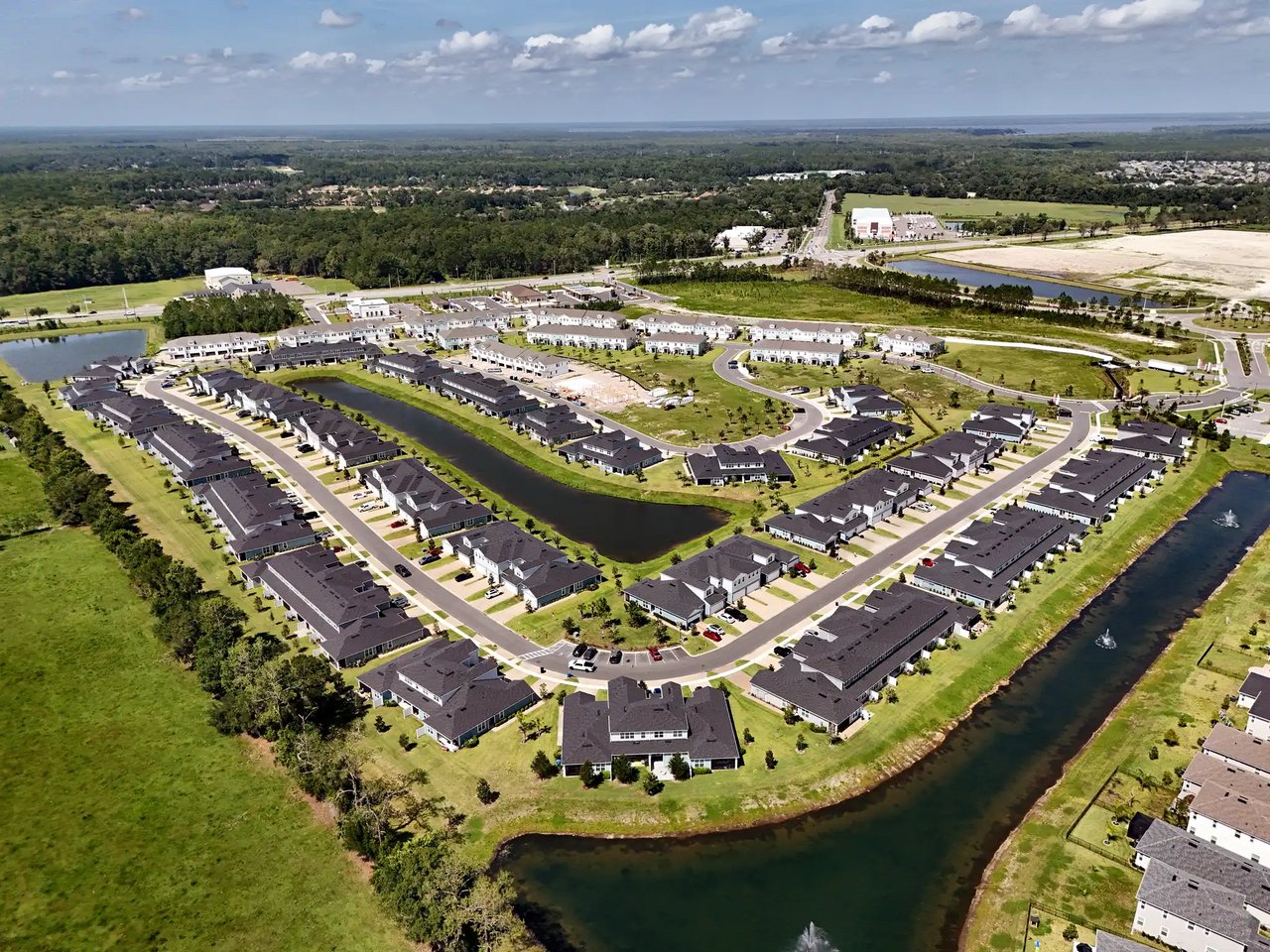 Aerial view of a residential community with curved streets, a central pond, and a canal.