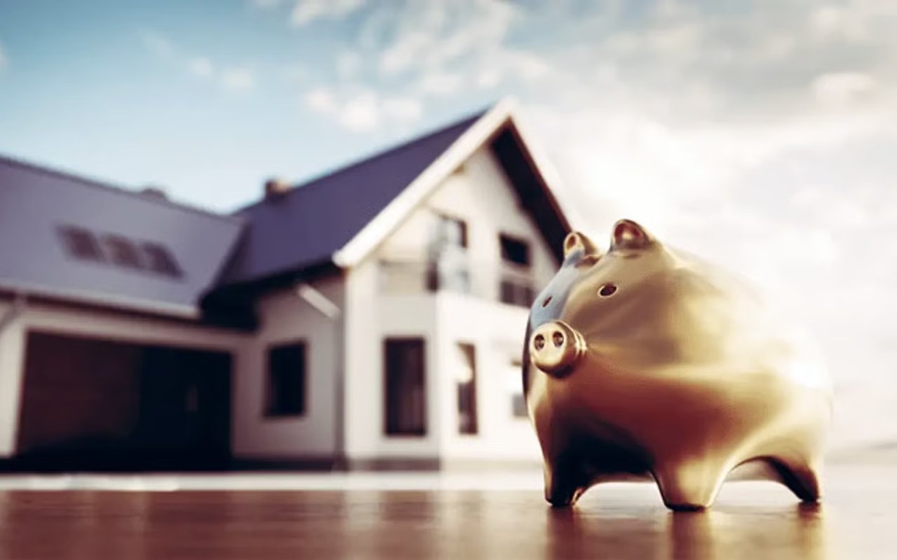 Gold piggy bank in front of a softly blurred house.