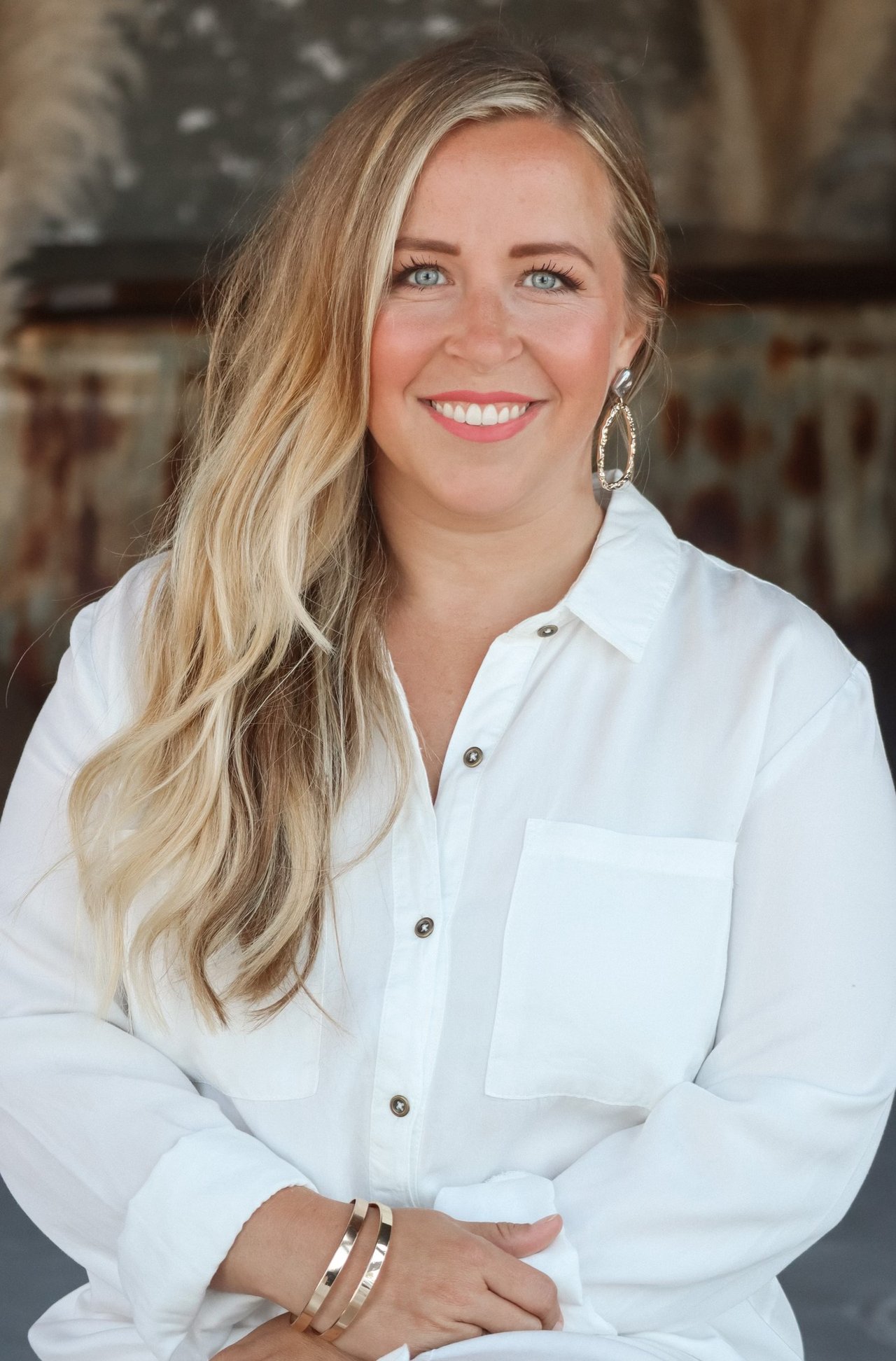 Britt Hildreth, smiling real estate agent with long blonde hair, wearing a white blouse.