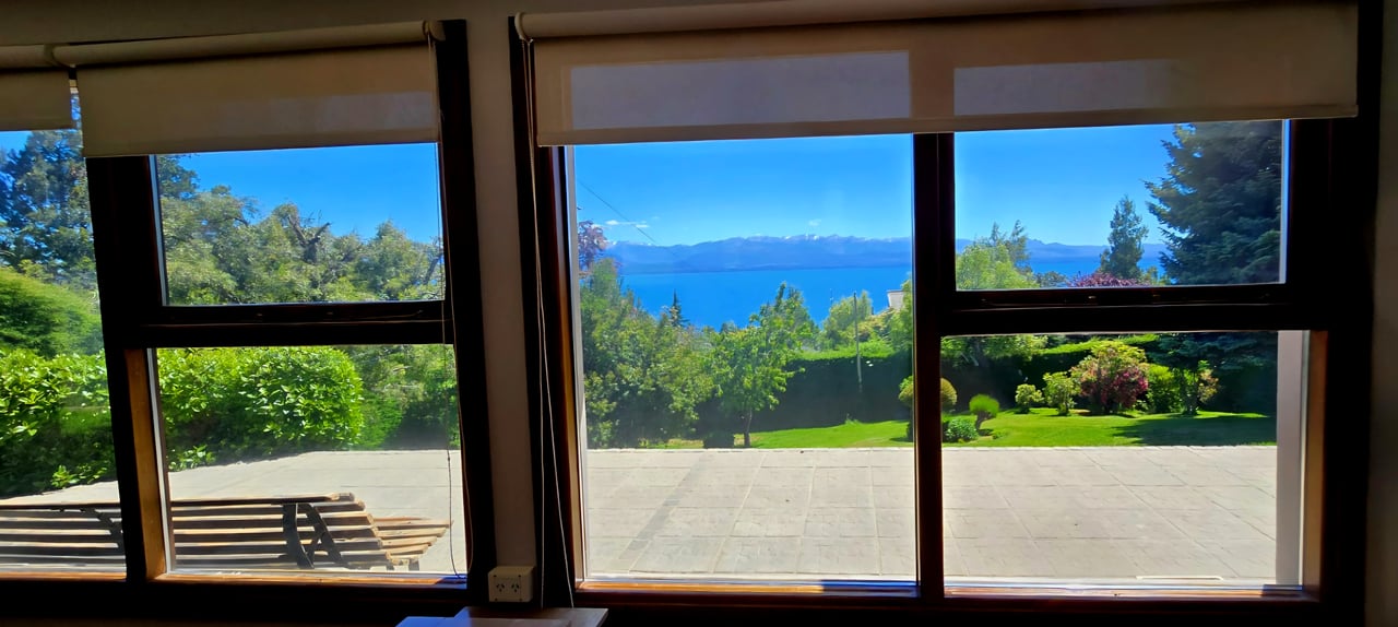 Lake and mountain view through large windows above a landscaped garden and terrace.
