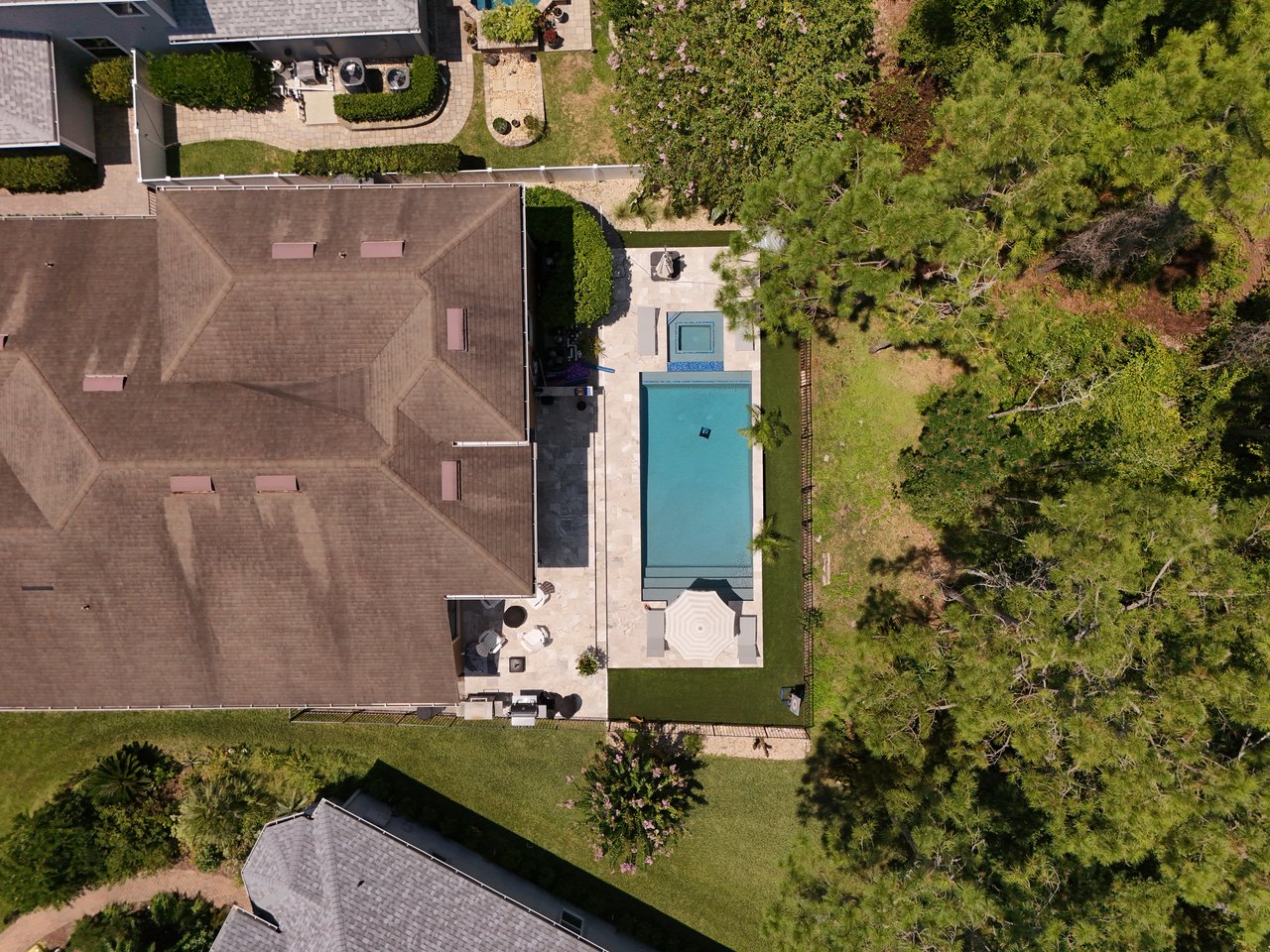Aerial view of a home with a backyard pool, spa, and paved patio.