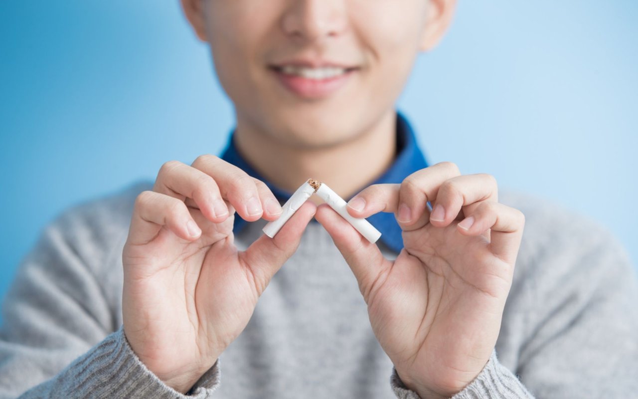 A person breaks a cigarette in half with both hands.