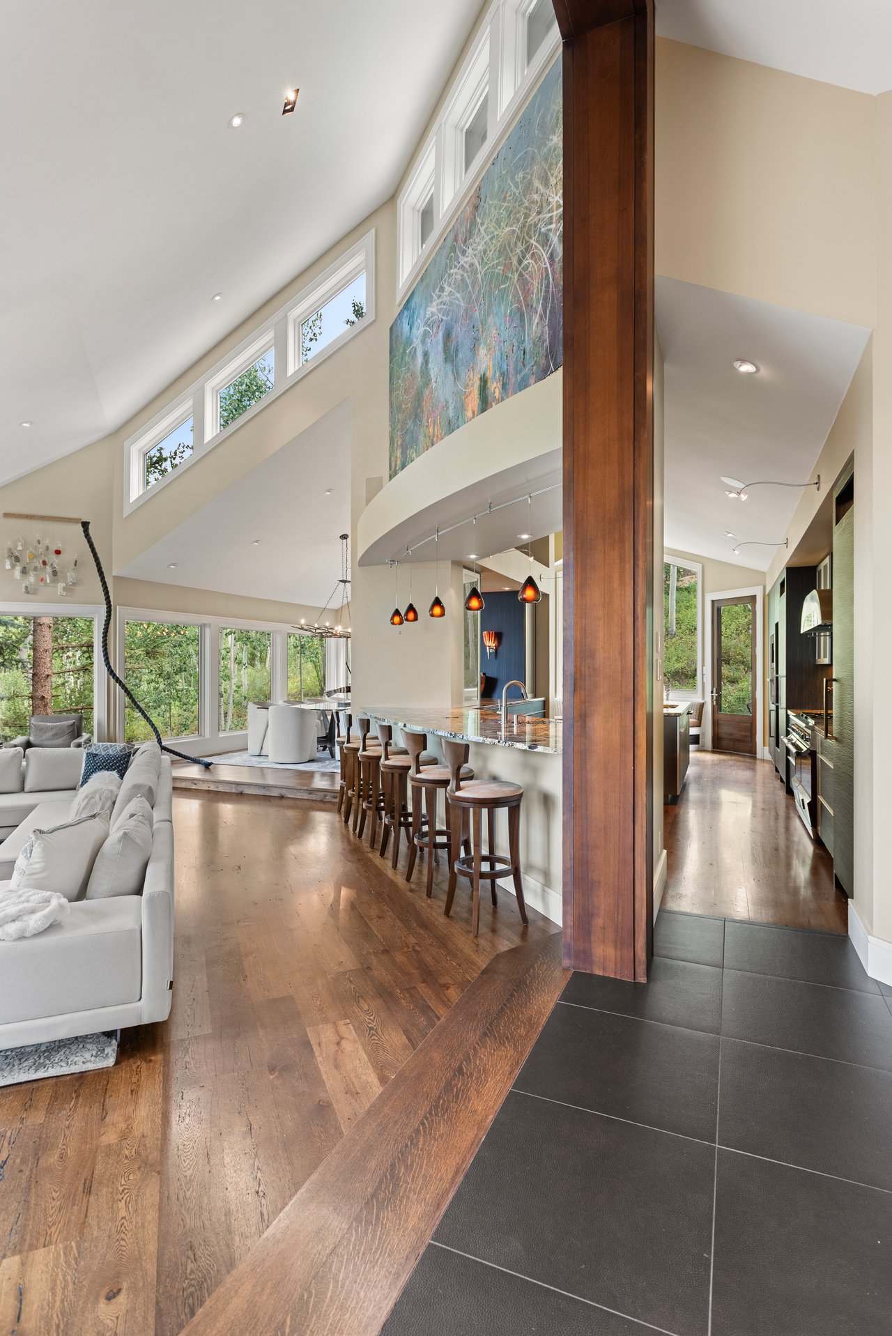 Open-plan living room and kitchen with vaulted ceiling, clerestory windows, and a large abstract mural.