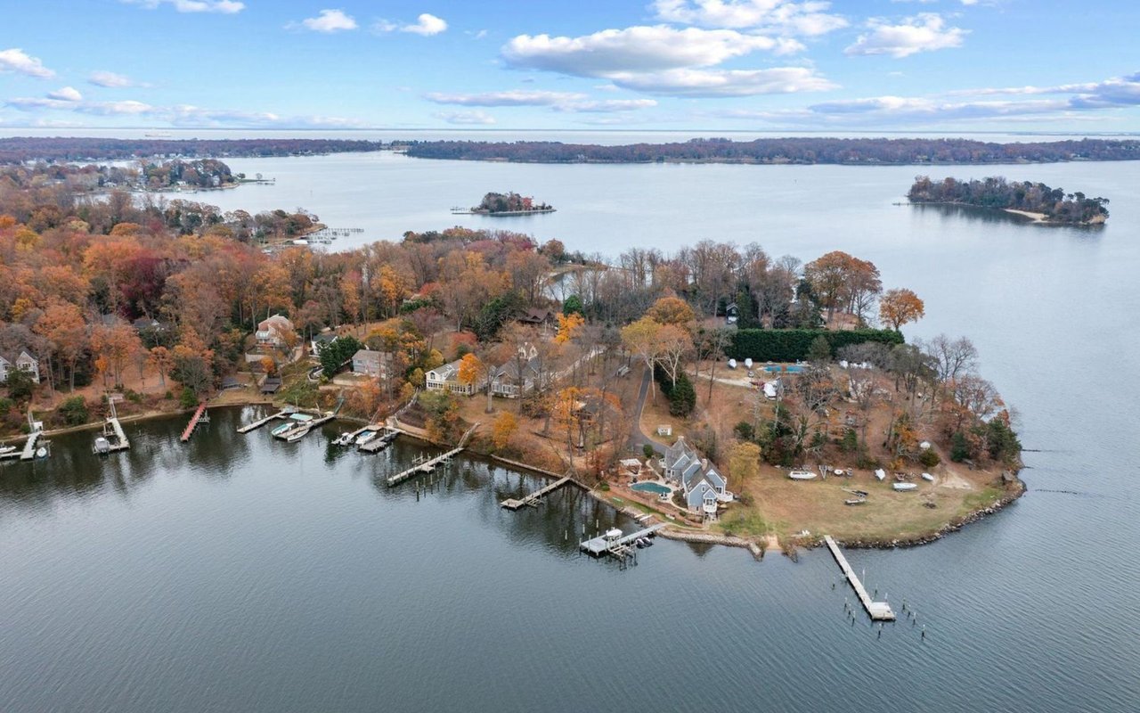 Aerial view of waterfront homes and docks on a wooded peninsula in autumn.