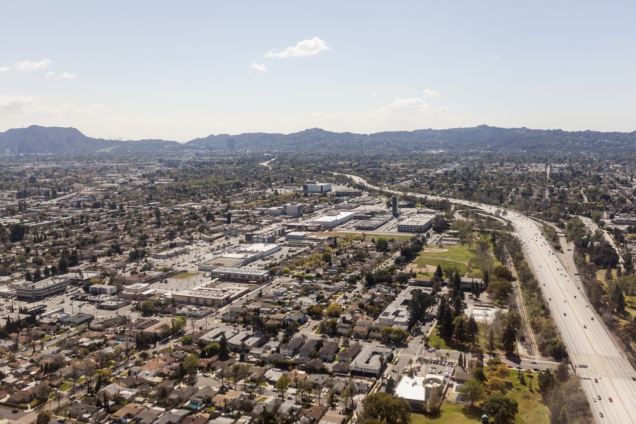Aerial view of North Hollywood neighborhoods, with a freeway winding toward distant hills.