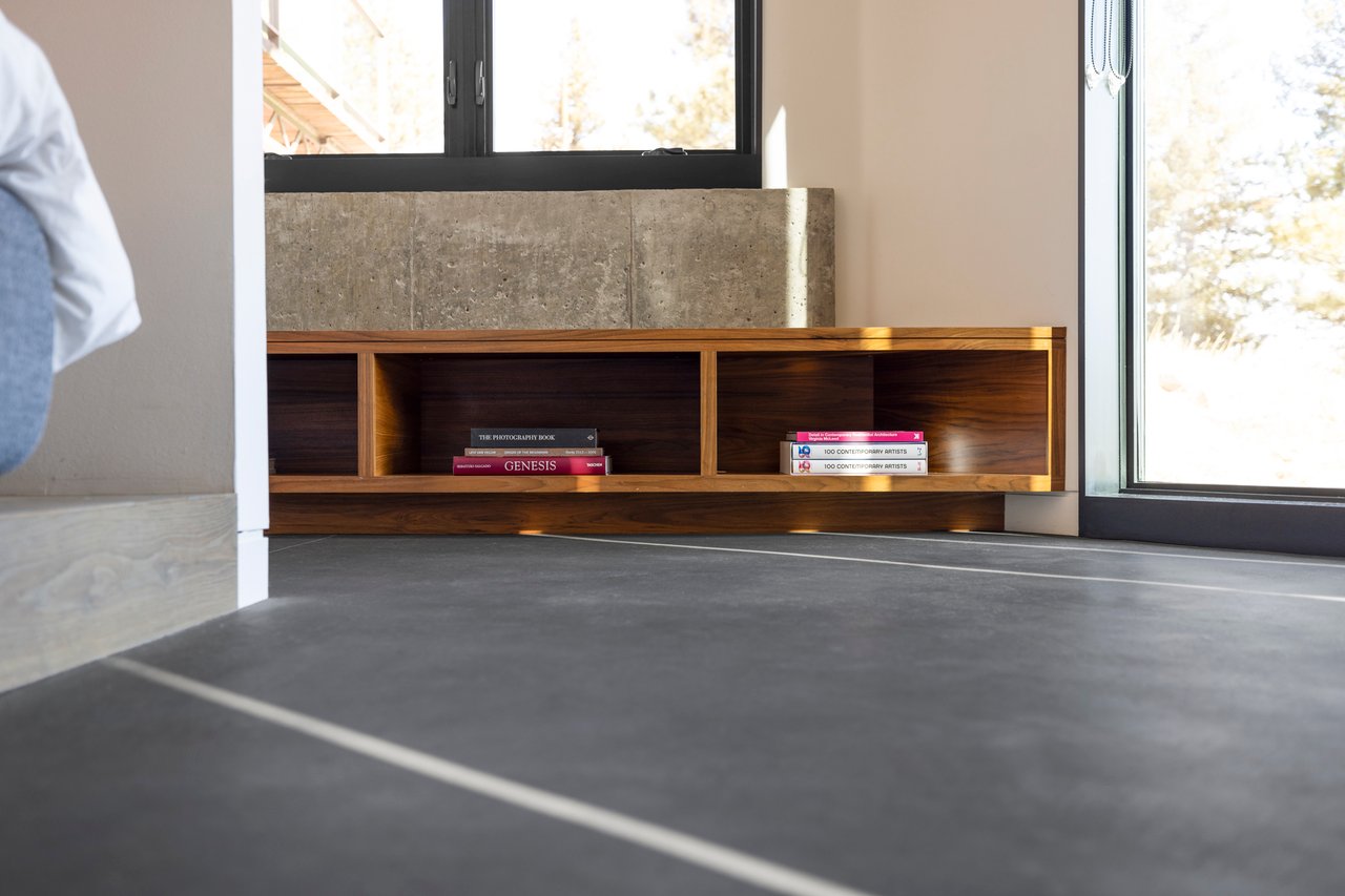 Custom wood bookshelf with concrete surround in Boulder bedroom featuring art and photography books