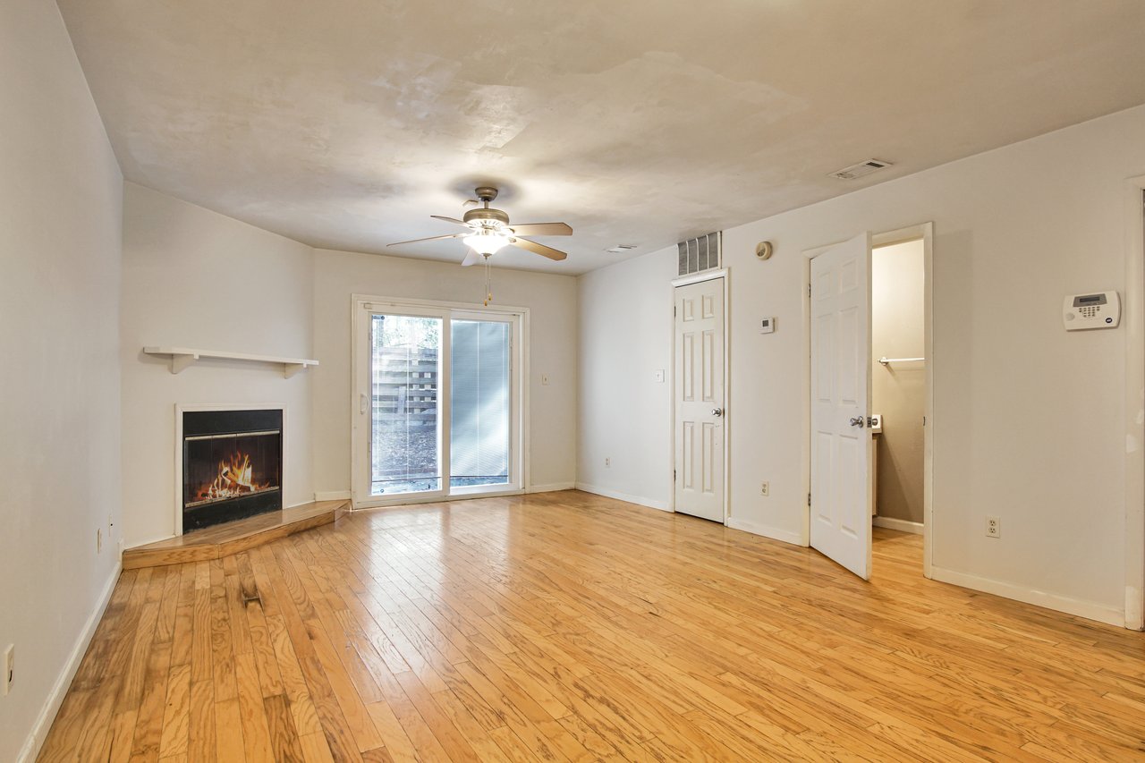 An empty room featuring hardwood floors and a classic fireplace, creating a serene and inviting atmosphere.