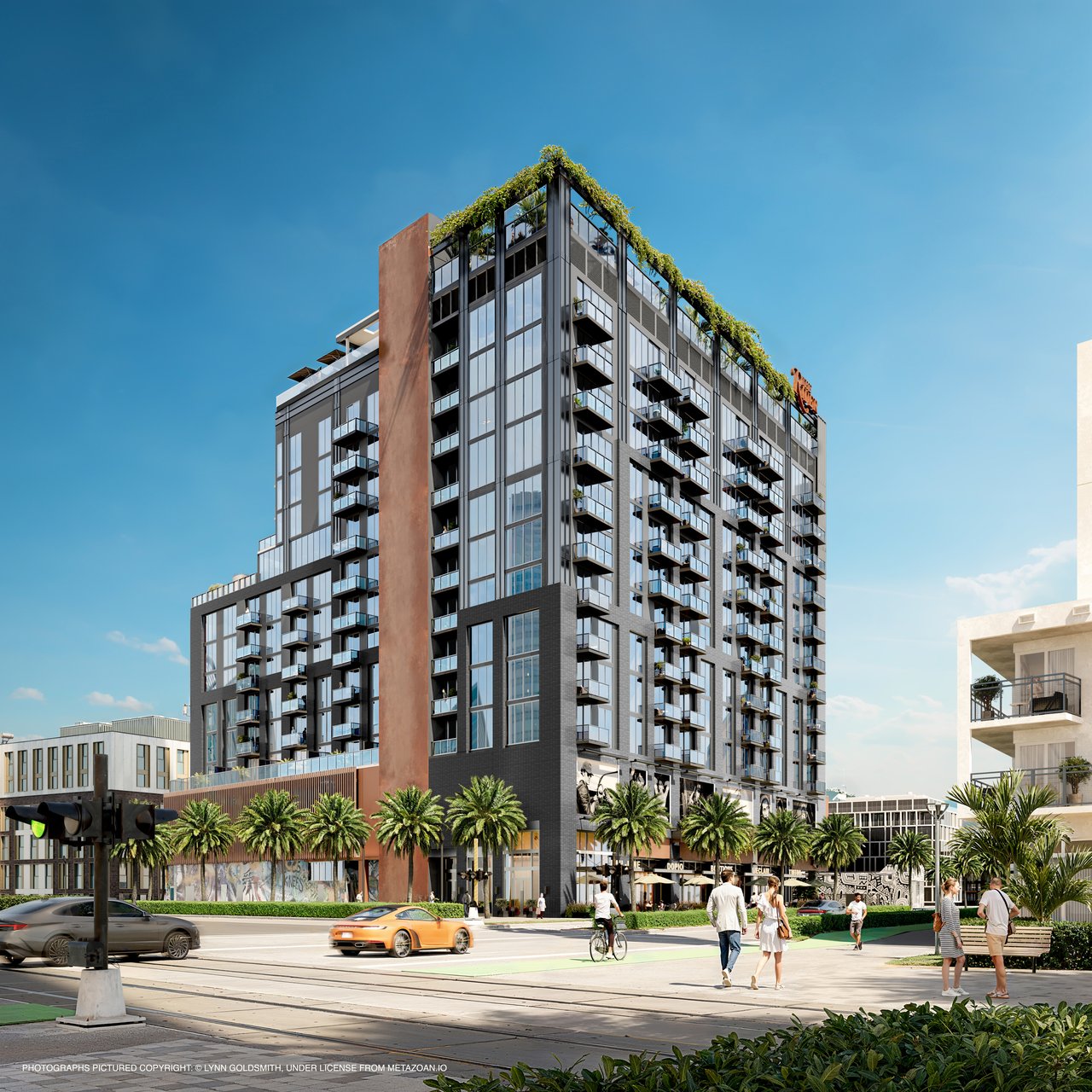 The Rider Residences, a glass-and-brick condominium with balconies and a landscaped rooftop above a palm-lined street.