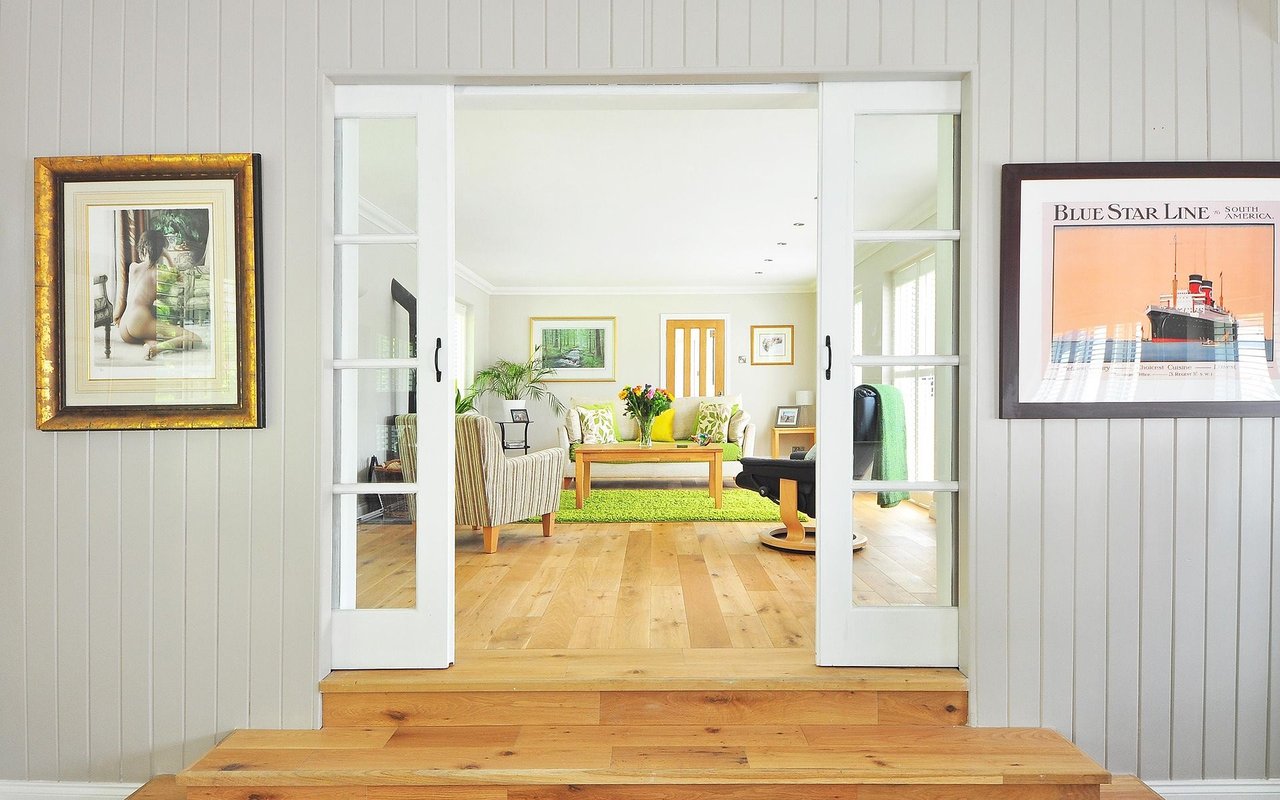 Furnished living room with open sliding doors, light wood floors, and a green rug.