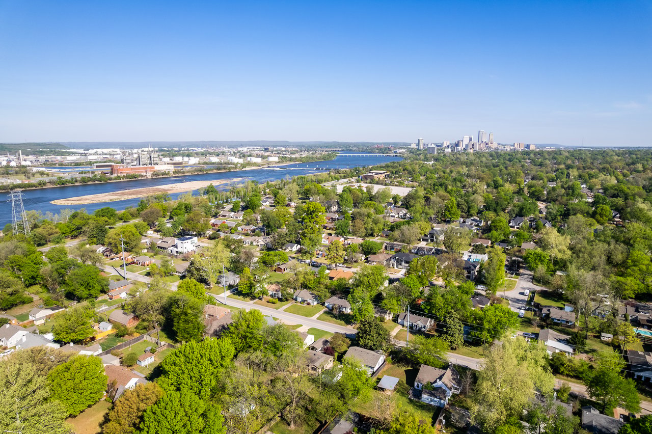 Aerial view of Tulsa’s leafy neighborhoods, the Arkansas River, and downtown skyline.