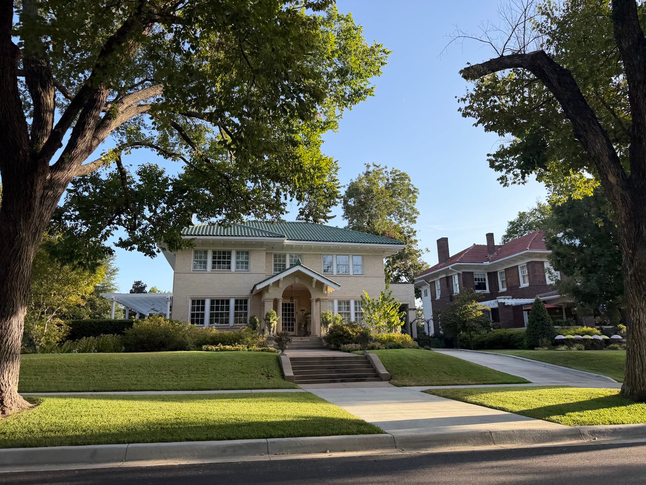 Ryan Place homes framed by mature trees, including a light-colored house with a green tile roof.