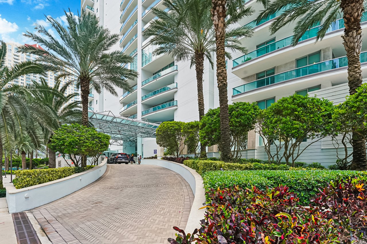 Palm-lined arrival drive leading to the glass-canopy entrance at Jade Residences at Brickell Bay