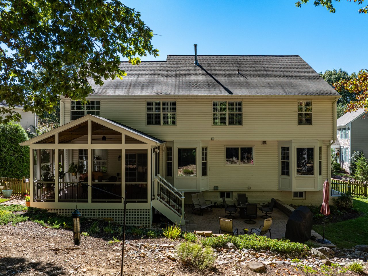 Rear exterior of a two-story home with a covered porch and stone patio.