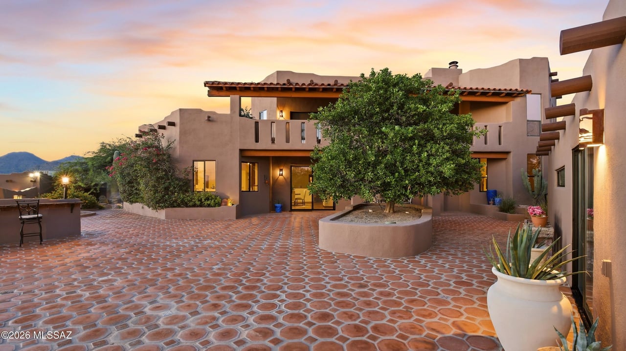 Pasos del Cielo home with a tiled courtyard, central tree, and mountains at sunset.