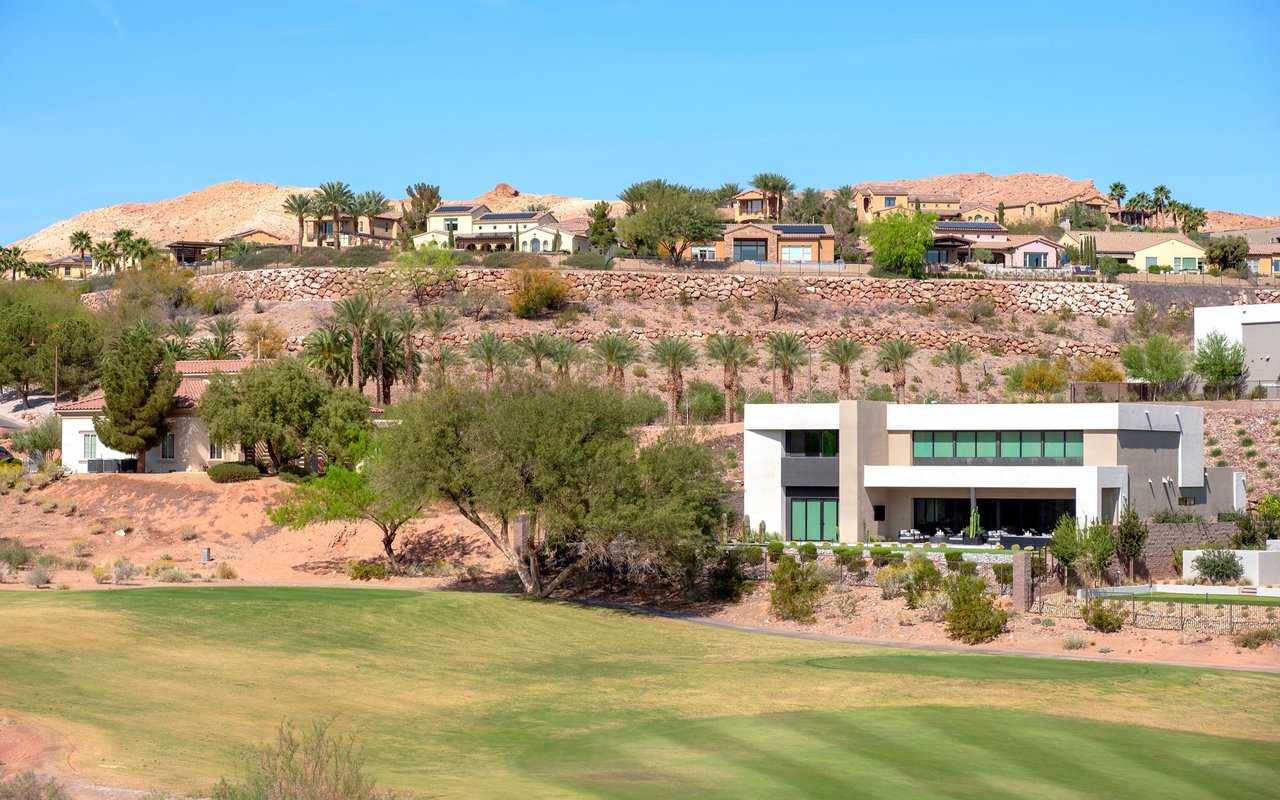Golf course below modern homes on a rocky desert hillside.