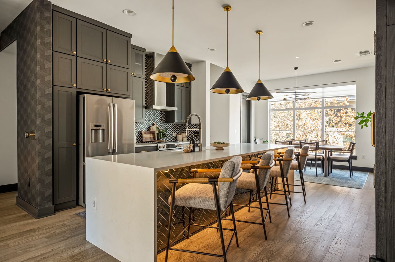 Kitchen and dining area at 4507 Unity Circle in The Grove, Austin, with a waterfall island, brass pendant lighting, and island seating, upgrades by Ashley Walker Designs.