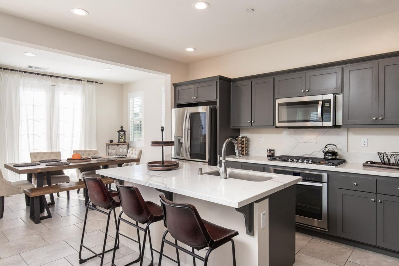 Kitchen with dark gray cabinets, stainless steel appliances, and a white island with bar seating.