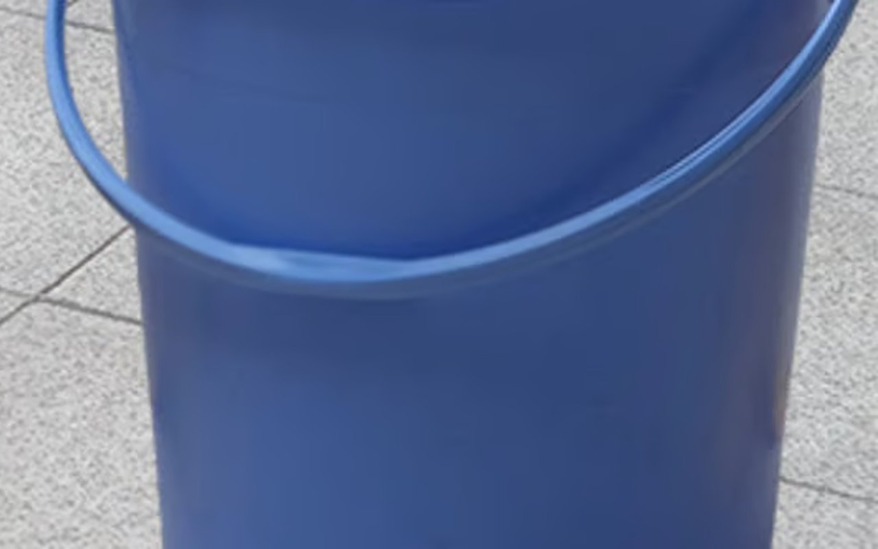 Blue plastic bucket on a tiled concrete surface.