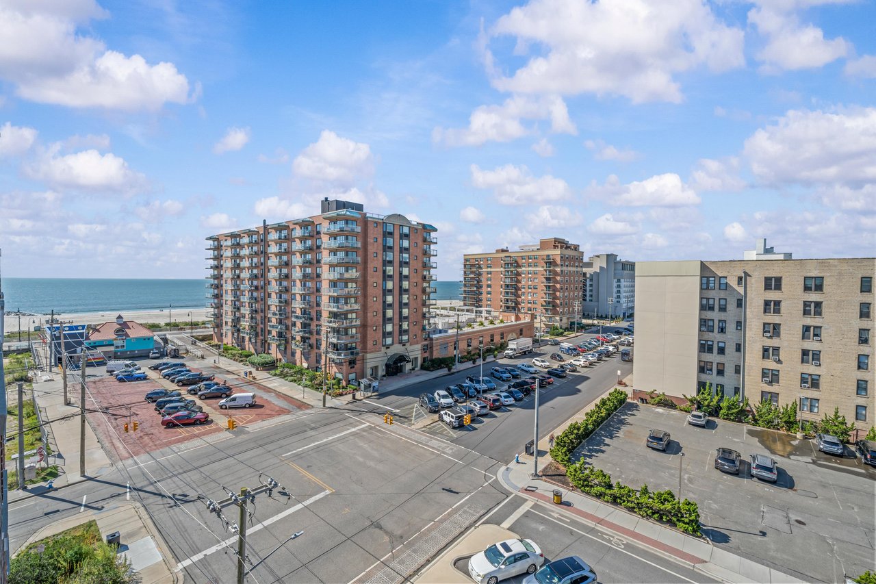 Elevated coastal view of apartment buildings and streets with the ocean beyond.