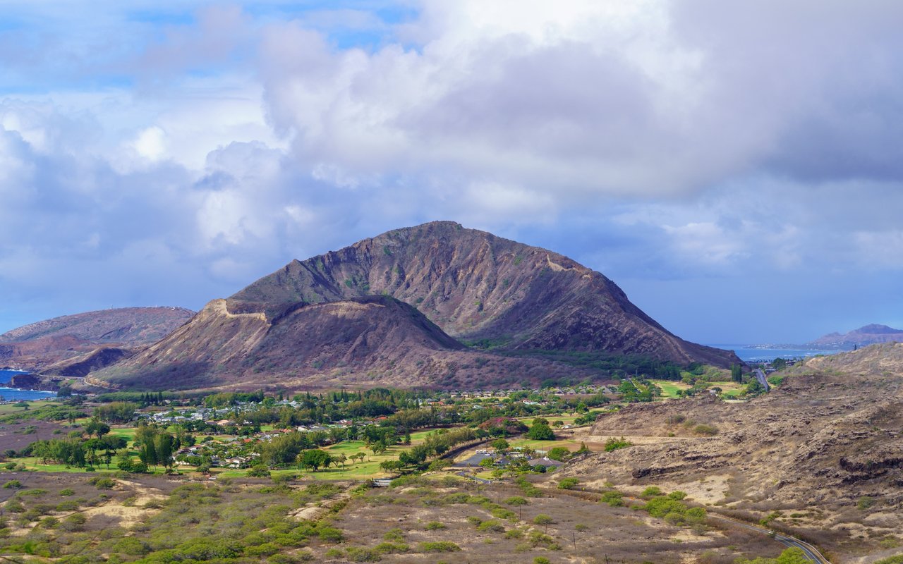 Rugged mountain ridge above a green neighborhood, with the coastline visible in the distance.